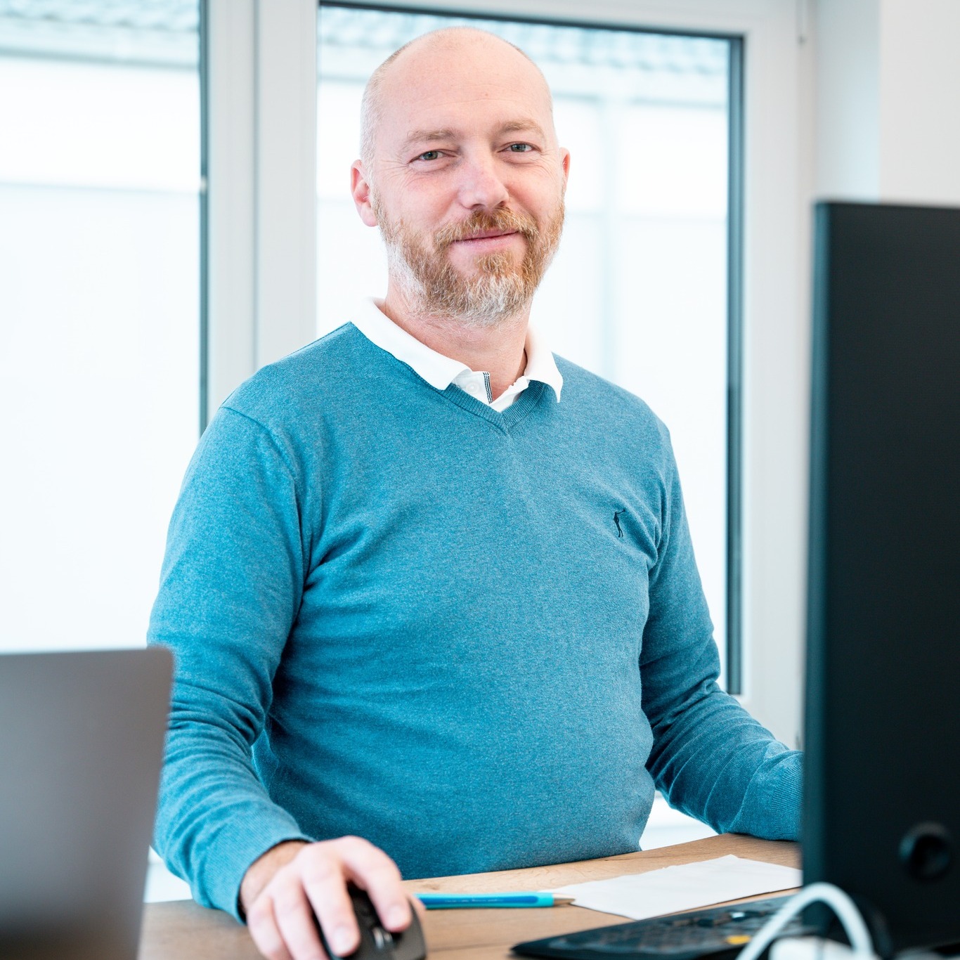 Geschäftsführer Christian Weber am Schreibtisch, konzentriert auf seine Arbeit am Computer in einem modernen Büro.